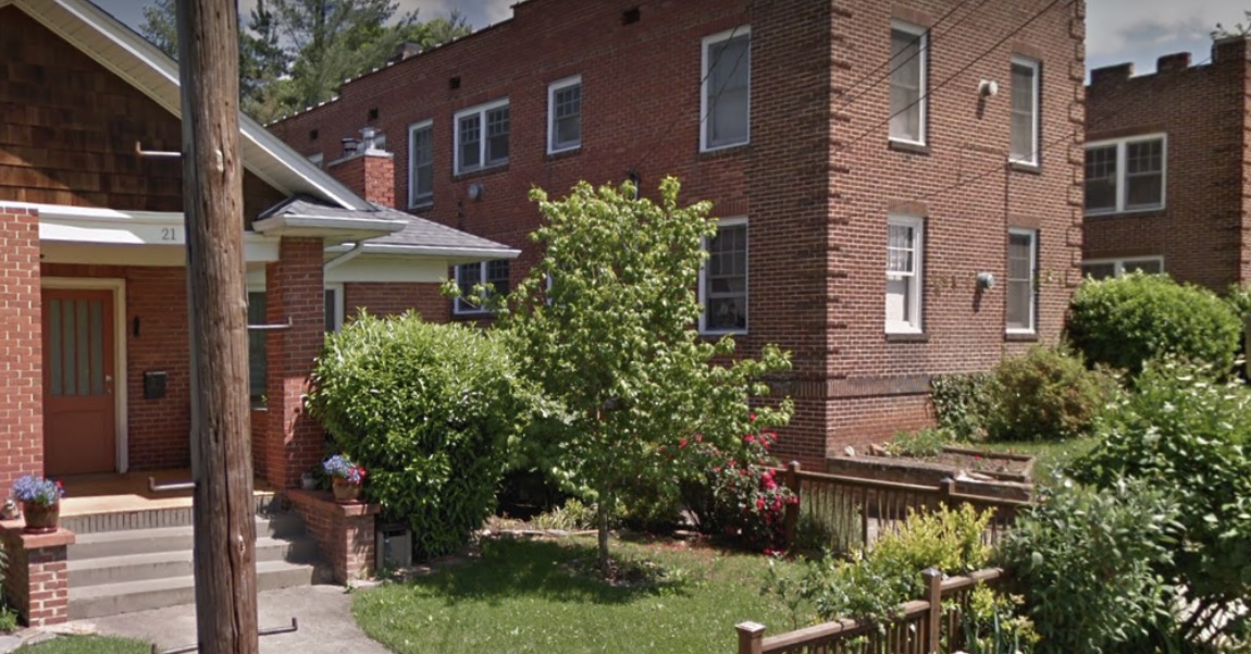 A small single-family home next to a larger apartment building on a tree-lined street.