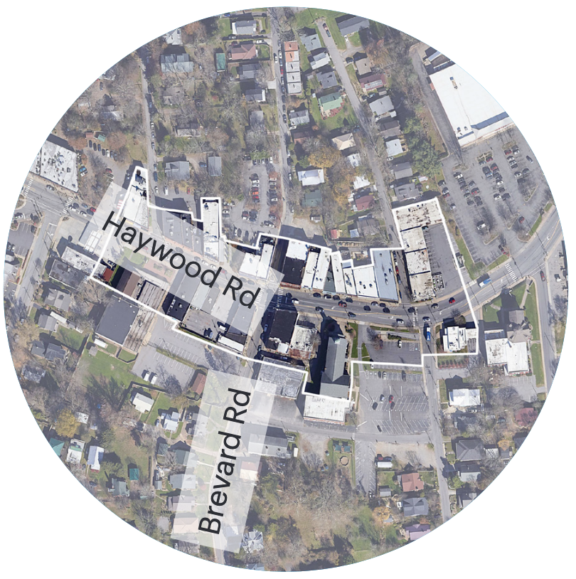 An aerial photograph of the intersection at Haywood Road and Brevard Road in West Asheville. Single family homes surround some commercial buildings at the intersection.
